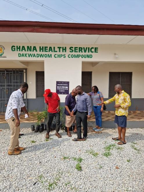 People gathered on the gravel compound of a health facility during a planting activity