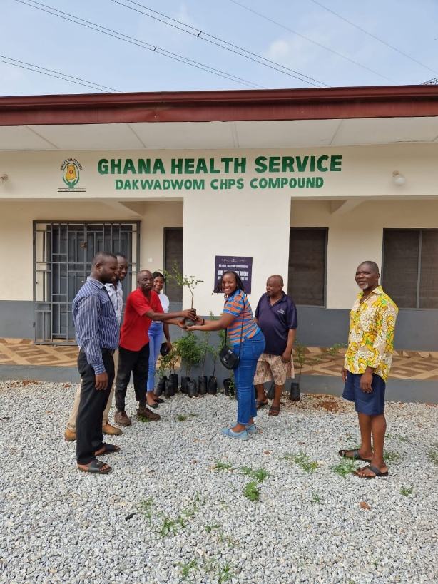 Volunteers and health facility staff standing in front of the Ghana Health Service Dakwadwom CHPS sign