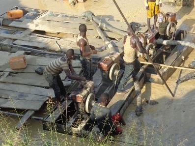 Workers operating equipment on wooden platforms at a riverside site