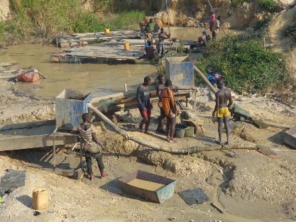 Workers and equipment along a muddy riverbank