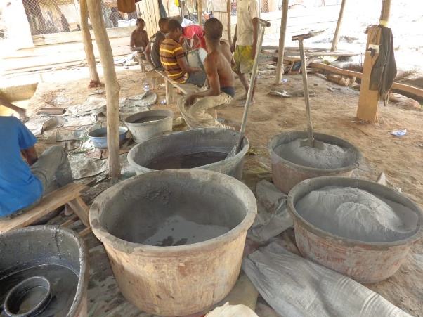 Workers gathered around large circular tubs at a processing site